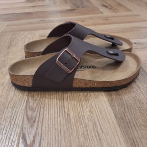 Ramses Dark Brown Le modèle Ramses Dark Brown est le pendant masculin de la très populaire Gizeh. En effet, sa bride à la coupe légèrement plus large confère aux sandales leur style original, masculin. Les sandales Birkenstock Ramses Birko-Flor sont un vrai classique. Le matériau supérieur est en Birko-Flor, un matériau synthétique résistant et doux pour la peau. Celui ci est présenté ici avec un look nubuck élégant presque identique au cuir véritable, à la fois dans la texture et la couleur. L’histoire de Birkenstock Tout commence en 1774, lorsque Johann Adam Birkenstock, un cordonnier allemand passionné, fonde ce qui allait devenir l'une des marques de chaussures les plus emblématiques au monde. À l'époque, Johann menait une petite entreprise modeste qui lui permettait de vivre confortablement. Mais comment cette production familiale a-t-elle pu se transformer en un empire mondial de la chaussure ? Le tournant se produit en 1896 avec Konrad Birkenstock, un descendant de la famille. Konrad, visionnaire, décide de donner un coup de jeune à l'entreprise familiale. C'est lui qui a développé la première semelle intérieure orthopédique, une innovation qui a littéralement mis le sabot Birkenstock sur la carte mondiale. Cependant, il aura fallu plusieurs générations et une évolution constante pour que Birkenstock devienne la marque internationale que l'on connaît aujourd'hui. Le grand bond en avant s’est produit au XXe siècle, notamment aux États-Unis dans les années 1960, où les sandales Birkenstock sont devenues un symbole de la contre-culture et du confort. Mais ce n'est pas seulement l'histoire de l'entreprise qui fascine, c'est aussi sa philosophie. Birkenstock s'engage à produire des chaussures qui respectent la santé de vos pieds, en mettant l'accent sur la posture et le confort. La marque prône une fabrication durable et éthique, en utilisant des matériaux naturels et écologiques. Tout cela, combiné à un savoir-faire artisanal de qualité, souvent fabriqué à la main en Allemagne, fait de Birkenstock une marque unique en son genre.