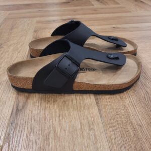 Ramses Black Le modèle Ramses Black est le pendant masculin de la très populaire Gizeh. En effet, sa bride à la coupe légèrement plus large confère aux sandales leur style original, masculin. Les sandales Birkenstock Ramses Birko-Flor sont un vrai classique. Le matériau supérieur est en Birko-Flor, un matériau synthétique résistant et doux pour la peau. Celui ci est présenté ici avec un look nubuck élégant presque identique au cuir véritable, à la fois dans la texture et la couleur. L’histoire de Birkenstock Tout commence en 1774, lorsque Johann Adam Birkenstock, un cordonnier allemand passionné, fonde ce qui allait devenir l'une des marques de chaussures les plus emblématiques au monde. À l'époque, Johann menait une petite entreprise modeste qui lui permettait de vivre confortablement. Mais comment cette production familiale a-t-elle pu se transformer en un empire mondial de la chaussure ? Le tournant se produit en 1896 avec Konrad Birkenstock, un descendant de la famille. Konrad, visionnaire, décide de donner un coup de jeune à l'entreprise familiale. C'est lui qui a développé la première semelle intérieure orthopédique, une innovation qui a littéralement mis le sabot Birkenstock sur la carte mondiale. Cependant, il aura fallu plusieurs générations et une évolution constante pour que Birkenstock devienne la marque internationale que l'on connaît aujourd'hui. Le grand bond en avant s’est produit au XXe siècle, notamment aux États-Unis dans les années 1960, où les sandales Birkenstock sont devenues un symbole de la contre-culture et du confort. Mais ce n'est pas seulement l'histoire de l'entreprise qui fascine, c'est aussi sa philosophie. Birkenstock s'engage à produire des chaussures qui respectent la santé de vos pieds, en mettant l'accent sur la posture et le confort. La marque prône une fabrication durable et éthique, en utilisant des matériaux naturels et écologiques. Tout cela, combiné à un savoir-faire artisanal de qualité, souvent fabriqué à la main en Allemagne, fait de Birkenstock une marque unique en son genre.