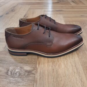Redskins Summit Cognac La marque Redskins propose une collection de chaussures pour homme et femme qui associe style urbain, confort et qualité des matières. Inspirées par l’univers du cuir et de la mode casual, les chaussures Redskins s’adaptent à différents styles et occasions, du quotidien aux moments plus habillés. L'histoire de la marque Lorsque l’on parle de la célèbre marque de cuir Redskins, on pense immédiatement au look américain, au style biker avec ce petit côté rock’n roll qui souligne la tenue masculine. Or c’est bel et bien en France qu’est née la marque, créée par Serge ABOUJEDID. C’est donc en 1984 que la marque Redskins voit le jour, inspirée de la culture américaine et de la tendance rock’n roll, empreint d’une touche contemporaine dans chaque création de la marque. Cette marque résolument française est née à Gennevilliers et oriente ses collections vers la fabrication de blousons et vestes en cuir pour homme. A partir des année 90, la marque a mis au gout du jour le modèle teddy Redskins, qui n’a de cesse d’être la pièce indémodable de votre garde-robe. Aujourd’hui, stylistes et créateurs ont choisi de diversifier leur gamme pour proposer des chaussures en cuir Redskins, la maroquinerie et divers accessoires à la vente. Une stratégie payante puisque la marque devient aujourd’hui la référence du cuir de qualité. Toujours enclin à suivre le mouvement culturel et notamment cinématographique, Redskins n’hésite pas à s’associer à des personnalités influentes pour proposer ses créations au grand public. Shemar Moore, David Duchovny ou encore Johnny Hallyday ont fait partie de leur figure pour représenter leur collection.