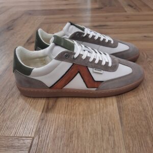 Redskins Eldorado Ecru Les Sneakers Redskins Eldorado Ecru allient style contemporain et confort optimal pour un look urbain affirmé. Leur dessus en cuir est sublimé par une double finition combinant empiècement en daim et surface lisse, apportant élégance, modernité et robustesse. La doublure et la semelle intérieure, associant textile et synthétique, garantissent confort et légèreté tout au long de la journée, tandis que la semelle intérieure amovible permet un ajustement personnalisé ou l’ajout de semelles spécifiques. La fermeture à lacets assure un maintien précis et sécurisé pour chaque pied. Polyvalentes et tendance, ces sneakers s’intègrent parfaitement à un style casual ou streetwear, offrant à la fois praticité, performance et esthétique raffinée pour un usage quotidien. L'histoire de la marque Lorsque l’on parle de la célèbre marque de cuir Redskins, on pense immédiatement au look américain, au style biker avec ce petit côté rock’n roll qui souligne la tenue masculine. Or c’est bel et bien en France qu’est née la marque, créée par Serge ABOUJEDID. C’est donc en 1984 que la marque Redskins voit le jour, inspirée de la culture américaine et de la tendance rock’n roll, empreint d’une touche contemporaine dans chaque création de la marque. Cette marque résolument française est née à Gennevilliers et oriente ses collections vers la fabrication de blousons et vestes en cuir pour homme. A partir des année 90, la marque a mis au gout du jour le modèle teddy Redskins, qui n’a de cesse d’être la pièce indémodable de votre garde-robe. Aujourd’hui, stylistes et créateurs ont choisi de diversifier leur gamme pour proposer des chaussures en cuir Redskins, la maroquinerie et divers accessoires à la vente. Une stratégie payante puisque la marque devient aujourd’hui la référence du cuir de qualité. Toujours enclin à suivre le mouvement culturel et notamment cinématographique, Redskins n’hésite pas à s’associer à des personnalités influentes pour proposer ses créations au grand public. Shemar Moore, David Duchovny ou encore Johnny Hallyday ont fait partie de leur figure pour représenter leur collection.