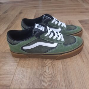 vans rowley vert-Chaussures Rowley Classic-Sneakers ROWLEY VANS Homme-L’histoire de Vans débute en 1966, lorsqu’un certain Paul Van Doren, accompagné de son frère Jim Van Doren et de deux associés, Gordon Lee et Serge Delia, décide d’ouvrir un magasin de chaussures à Anaheim, en Californie. Contrairement aux autres fabricants de chaussures de l’époque, Vans adopte un concept novateur : elle fabrique et vend directement ses propres produits, supprimant ainsi les intermédiaires. La première boutique propose alors un modèle unique, sobrement appelé « Vans #44 Deck Shoes », qui deviendra plus tard la célèbre Authentic. Très vite, la marque attire l’attention des skateurs californiens, séduits par l’adhérence exceptionnelle de la semelle en caoutchouc gaufré et la robustesse des chaussures. Le bouche-à-oreille fonctionne et Vans devient rapidement une référence incontournable dans le monde du skateboard, un sport encore en plein essor à cette époque. Grâce à cette popularité naissante, l’entreprise commence à développer de nouveaux modèles et à se diversifier, jusqu’à devenir l’icône que l’on connaît aujourd’hui.