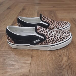 Classic Slip On Léopard Lancée en 1977 sous le nom de Vans #98, la Classic Slip-On est rapidement devenue une icône en Californie du Sud, puis a défini un style décontracté à l’échelle mondiale. Reconnue pour sa silhouette intemporelle, confortable et facile à porter, cette basket classique incarne l’ADN Vans à chaque pas. Dotée d’une tige en toile et en daim robuste et ornée de notre imprimé léopard, elle est idéale pour adopter un style décontracté et original. La création de Vans L’histoire de Vans débute en 1966, lorsqu’un certain Paul Van Doren, accompagné de son frère Jim Van Doren et de deux associés, Gordon Lee et Serge Delia, décide d’ouvrir un magasin de chaussures à Anaheim, en Californie. Contrairement aux autres fabricants de chaussures de l’époque, Vans adopte un concept novateur : elle fabrique et vend directement ses propres produits, supprimant ainsi les intermédiaires. La première boutique propose alors un modèle unique, sobrement appelé « Vans #44 Deck Shoes », qui deviendra plus tard la célèbre Authentic. Très vite, la marque attire l’attention des skateurs californiens, séduits par l’adhérence exceptionnelle de la semelle en caoutchouc gaufré et la robustesse des chaussures. Le bouche-à-oreille fonctionne et Vans devient rapidement une référence incontournable dans le monde du skateboard, un sport encore en plein essor à cette époque. Grâce à cette popularité naissante, l’entreprise commence à développer de nouveaux modèles et à se diversifier, jusqu’à devenir l’icône que l’on connaît aujourd’hui