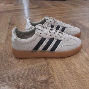 Barreda Decode Beige Incarne l'héritage d’adidas avec la chaussure Barreda Decode, une fusion de design classique inspiré du style « terrace » et de touche contemporaine. Le daim et le cuir de première qualité s'associent pour créer une silhouette pointue qui rehausse les looks streetwear de tous les jours. La construction de la semelle cupsole offre un confort tout au long de la journée, tandis que la fermeture à lacets permet un ajustement personnalisé. La semelle extérieure en caoutchouc durable offre stabilité et adhérence, ce qui la rend aussi pratique qu'élégante. Les détails emblématiques d'adidas, y compris les 3 bandes incomparables, complètent le design, pour un clin d'œil subtil à l'héritage de la marque. Cette chaussure véhicule de l'assurance et du caractère, c’est un must-have des fashionistas. La marque C'est le 18 août 1949 qu'Adi Dassler a démarré l'aventure adidas, avec pour objectif d'améliorer les performances des athlètes. 70 ans plus tard, adidas a laissé sa marque sur le monde du sport, mais aussi celui de la mode, de la musique, de la culture, du développement durable et bien d'autres encore. Voyage avec nous à travers le temps et découvre l'histoire d'adidas avec des modèles qui ont influencé le lifestyle d'aujourd'hui. Juste après la naissance officielle des 3 bandes en 1949, les années 50 ont connu un véritable boom technologique avec des équipements innovants pour les athlètes de classe mondiale. Ainsi, c'est pendant cette décennie qu'est apparue la Samba, toujours portée de nos jours pas les joueurs de Five et de futsal, et toujours présente dans la rue. Pendant les 50's, adidas a développé une chaussure de sprint qui a battu un record du monde et la première chaussure de football conçue avec une semelle en nylon, marquant une vraie nouveauté en termes de confort et de sensations. D'autres modèles ont vu le jour durant cette période, comme la chaussure de basketball Allround, devenue une véritable icône dans les 80's. Ces années ont été révolutionnaires, créant un véritable avant et après pour les sportifs de haut niveau. Mais ce n'était que le début de l'histoire d'adidas