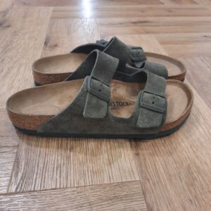 Arizona Thym L’Arizona Thym, classique BIRKENSTOCK au design intemporel, comble hommes et femmes depuis des décennies. Les détails et les boucles de couleur assortie au toucher textile d’aspect mat lui confèrent une petite touche d’originalité supplémentaire. Sa tige se compose de cuir velours doux. L’histoire de Birkenstock Tout commence en 1774, lorsque Johann Adam Birkenstock, un cordonnier allemand passionné, fonde ce qui allait devenir l'une des marques de chaussures les plus emblématiques au monde. À l'époque, Johann menait une petite entreprise modeste qui lui permettait de vivre confortablement. Mais comment cette production familiale a-t-elle pu se transformer en un empire mondial de la chaussure ? Le tournant se produit en 1896 avec Konrad Birkenstock, un descendant de la famille. Konrad, visionnaire, décide de donner un coup de jeune à l'entreprise familiale. C'est lui qui a développé la première semelle intérieure orthopédique, une innovation qui a littéralement mis le sabot Birkenstock sur la carte mondiale. Cependant, il aura fallu plusieurs générations et une évolution constante pour que Birkenstock devienne la marque internationale que l'on connaît aujourd'hui. Le grand bond en avant s’est produit au XXe siècle, notamment aux États-Unis dans les années 1960, où les sandales Birkenstock sont devenues un symbole de la contre-culture et du confort.