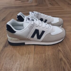 New Balance 574 White Découvrez l’alliance parfaite entre élégance intemporelle et innovation moderne avec cette paire New Balance 574 White. D'abord, sa couleur métallisée bronze rehaussée de détails noirs confère à votre tenue une touche sophistiquée. De plus, c'est la paire idéale pour sublimer aussi bien un look décontracté qu’urbain. La matière supérieure, composée de suède et de matériaux synthétiques, offre une durabilité remarquable et un confort optimal tout au long de la journée. La semelle intermédiaire intègre un amorti léger en EVA, garantissant une absorption des chocs efficace, tandis que la semelle extérieure en caoutchouc recyclé assure une adhérence fiable sur toutes les surfaces. Le mesh en polyester recyclé favorise la respirabilité, tout en répondant à une démarche éco-responsable. Grâce au renfort au talon, la stabilité est accrue, et la fermeture à lacets permet un ajustement personnalisé. L’emblématique logo “N” sur le côté et la languette rappellent l’héritage unique de la marque. En conclusion, ce modèle convient aux femmes à la recherche d’un équilibre parfait entre style, confort et conscience environnementale. Ces baskets deviendront vite un incontournable de votre garde-robe. La marque New balance est une marque authentique depuis en 1906. Elle produit et fabrique des chaussures dans tous les domaines sportifs. Ce qui fait de New Balance la plus grande marque de chaussures au monde. Le nom New Balance est synonyme de qualité. Il n'est donc pas étonnant que la marque ait 100 ans d'histoire. Son slogan "a more intelligent approach to building shoes" décrit très bien l'éthique de l'entreprise. Les sneakers New Balance sont résolument orientées vers la meilleure performance possible, sans pour autant négliger l'aspect esthétique. Tous les produits ont cependant en commun la même idée de base : fournir le mélange parfait de performance et de mode. C'est exactement ce que les amateurs de New Balance apprécient.