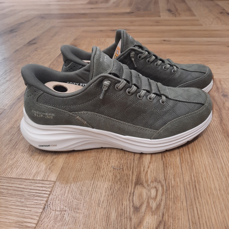 Contour Foam Kaki Offrez à vos pieds un confort parfait en portant la Skechers Hands Free Slip-ins® : Contour Foam Kaki - Cozy Fit™ Natural Ease. Conçue avec notre technologie Heel Pillow™, cette chaussure à enfiler présente une tige matelassée Cozy Fit™ en suède scintillant avec des lacets extensibles noués, un rembourrage Contour Foam™ dans la semelle intermédiaire et notre semelle intérieure coussinée Skechers Air-Cooled Memory Foam™. La marque Skechers, fondée en 1992 par Robert Greenberg à Manhattan Beach, en Californie, est rapidement devenue l'une des marques les plus reconnues dans l'industrie des chaussures et du sport. Connue pour ses designs innovants, son confort exceptionnel et ses collaborations créatives, Skechers est un acteur majeur dans le monde des chaussures sportives et de loisirs. L'histoire de Skechers commence modestement, avec des baskets à la fois sportives et stylées, destinées à offrir un confort maximal pour tous. Très vite, la marque s'impose comme un incontournable de la chaussure de sport, notamment grâce à ses technologies innovantes, telles que Memory Foam et Arch Fit, qui révolutionnent l'expérience du port de chaussures au quotidien. L'ADN de Skechers se construit sur une vision simple mais ambitieuse : offrir des produits alliant confort, style et performance.