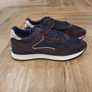 City Brown Navy La sneaker City Brown Navy est une silhouette urbaine conçue à partir d’une combinaison soignée de matériaux premium, de finitions de qualité et d’une palette de couleurs attractive. Pour commencer, elle est légère, stable et elle offre un excellent maintien. De plus, elle associe parfaitement praticité et élégance. Puis, sa semelle intérieure en Memory Foam s’adapte à la forme du pied et à la démarche pour un confort anatomique à chaque pas. Elle possède, une languette souple et un talon rembourré, tous deux siglés du logo de la marque. La marque Fondée en Espagne en 2017, HOFF est née de la conviction que chaque pas est une opportunité de créer, découvrir et affirmer sa personnalité. HOFF est une marque contemporaine de sneakers qui marie un design intemporel et élégant avec une polyvalence audacieuse. Reconnue pour sa créativité raffinée, son attention aux détails et sa maîtrise unique des couleurs, HOFF crée des sneakers qui s’adaptent aux transitions de la vie, transformant chaque instant du quotidien en une expression de style et de sens. Inspirée par le mouvement et la curiosité, HOFF célèbre l’individualité et l’expression de soi à travers le design. Son esthétique distinctive équilibre sophistication et modernité, brouillant les frontières entre le décontracté et le raffiné, tout en restant fidèle à ses valeurs de connexion, d’authenticité, de passion et de créativité.