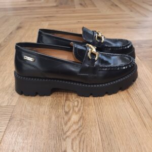Mocassins Valmer Noir Ces Mocassins Valmer Noir en cuir sont le parfait mélange entre raffinement et praticité. Disponibles en noir et chocolat, ils s’adaptent facilement à toutes vos tenues, du bureau à vos sorties en ville. Leur semelle crantée apporte une touche contemporaine tout en assurant une excellente stabilité. Le détail doré sur le dessus et les surpiqûres autour du bout renforcent le caractère chic du modèle. Confortables et stylés, ces mocassins sont idéaux pour un usage quotidien avec une touche d’élégance. Les Tropeziennes par M. Belarbi : L’histoire d’un style intemporel, né à Saint-Tropez Mo Belarbi, né à Fez, est un créateur visionnaire et passionné par le cuir, l’artisanat et les voyages. En 1975 dans le village emblématique de Saint-Tropez dont il tombe amoureux, il ouvre son premier concept store «La Puce Tropezienne», un lieu unique, foisonnant de créativité et d’audace. Mo Belarbi, esprit libre et innovant y imagine des modèles qui deviendront iconiques, intergénérationnels et s’imposeront rapidement comme incontournables.