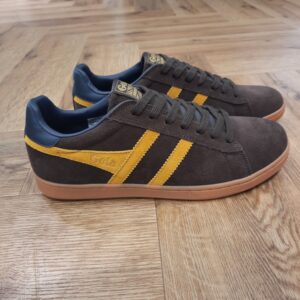 Gola Equipe Dark Brown En matière de baskets fiables, les Gola Equipe Dark Brown pour homme est un choix sûr. Monté sur une semelle en gomme, ce modèle à lacets en daim bleu marine épuré avec bordure en forme d'aile Gola gingembre est polyvalent et peut être facilement associé à des looks de tous les jours. La languette de talon en soleil foncé apporte une finition remarquable, équilibrant le moderne avec l'héritage authentique des baskets. La marque Gola est une marque principalement connue pour ses chaussures de sport. Elle a été créé en 1905 à Leicester, au Royaume Uni. Pour l'anecdote, personne ne sait exactement d'où vient le nom de la marque. Pourtant, une légende urbaine raconte qu'elle doit son nom à l'anagramme du mot "Goal" (qui signifie "but" en anglais). La marque commence à être connue à la fin des années 1960. Notamment dans le sport notamment avec la Harrier qui reste aujourd'hui encore le modèle phare de la marque anglaise. En effet, elle a très vite été adoptée par le grand public. Fort de son histoire, la marque a su traverser les générations et est aujourd'hui une marque streetwear à part entière qui sait innover et suivre les tendances. On a d'ailleurs pu voir une collection 100 % vegan sortir des tuyaux en 2019, preuve de la capacité de Gola à s'adapter au marché actuel !