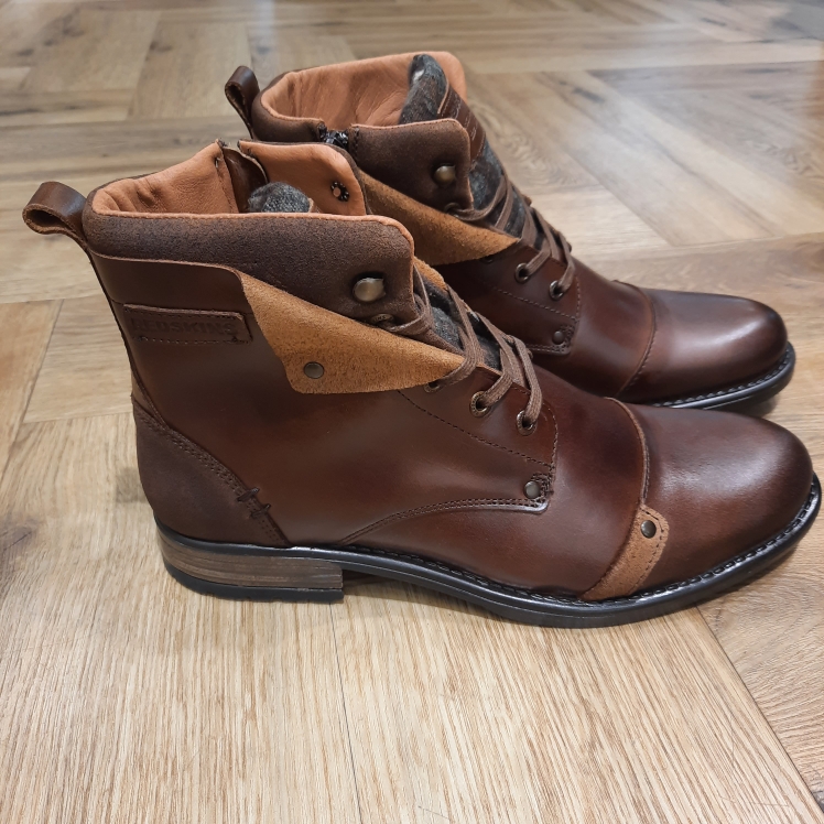 Boots Yedos Cognac Les Boots Yedos Cognac reprennent la ligne de la boot montante à lacets dans un cuir tabac patiné. La doublure et la languette en textile contrastent avec la teinte chaude de la tige, tandis que les crochets métalliques et les surpiqûres apparentes affirment le caractère utilitaire du modèle. De plus, la semelle épaisse à débord gomme complète l'ensemble. Cette paire se porte avec un jean brut, un chino épais ou un pantalon en velours côtelé, sous une parka. L'histoire de la marque Lorsque l’on parle de la célèbre marque de cuir Redskins, on pense immédiatement au look américain, au style biker avec ce petit côté rock’n roll qui souligne la tenue masculine. Or c’est bel et bien en France qu’est née la marque, créée par Serge ABOUJEDID. C’est donc en 1984 que la marque Redskins voit le jour, inspirée de la culture américaine et de la tendance rock’n roll, empreint d’une touche contemporaine dans chaque création de la marque. Cette marque résolument française est née à Gennevilliers et oriente ses collections vers la fabrication de blousons et vestes en cuir pour homme. A partir des année 90, la marque a mis au gout du jour le modèle teddy Redskins, qui n’a de cesse d’être la pièce indémodable de votre garde-robe. Aujourd’hui, stylistes et créateurs ont choisi de diversifier leur gamme pour proposer des chaussures en cuir Redskins, la maroquinerie et divers accessoires à la vente. Une stratégie payante puisque la marque devient aujourd’hui la référence du cuir de qualité. Toujours enclin à suivre le mouvement culturel et notamment cinématographique, Redskins n’hésite pas à s’associer à des personnalités influentes pour proposer ses créations au grand public. Shemar Moore, David Duchovny ou encore Johnny Hallyday ont fait partie de leur figure pour représenter leur collection.