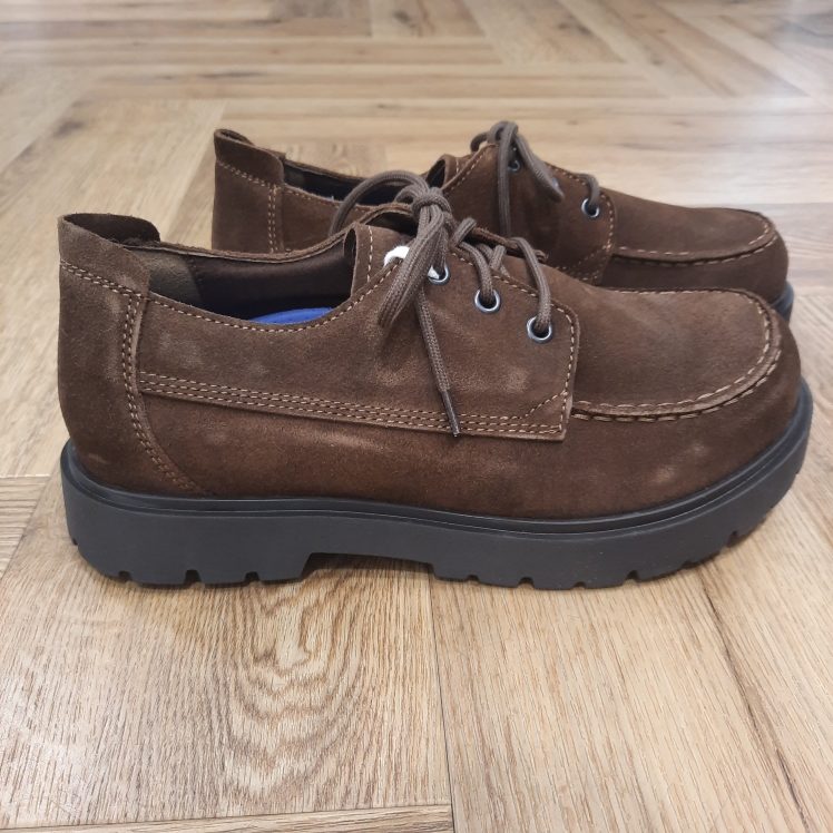 Highwood Moc Lace Low Avec les Highwood Moc Lace Low, BIRKENSTOCK lance un modèle sobre et tendance de chaussures basses. Pour commencer, leur laçage vous offre un bon maintien et une adaptabilité optimale. De plus, le lit de pied Deep Blue, confortable et léger, rend ces chaussures agréables à porter en toutes circonstances. Mais surtout durant de longues journées bien chargées, elles sont idéales pour les voyages, les longues balades et les escapades en ville. L’élément distinctif de cette variante est sa semelle en caoutchouc de grande qualité, dont le profil inspiré du monde professionnel offre une excellente adhérence. Les éléments profilés, placés de manière à soutenir les propriétés biomécaniques du pied, favorisent son déroulement naturel et assurent un maximum de confort lors de la marche. Puis, sa tige est confectionnée dans un cuir velours particulièrement doux qui drape le pied comme une seconde peau. L’histoire de Birkenstock Tout commence en 1774, lorsque Johann Adam Birkenstock, un cordonnier allemand passionné, fonde ce qui allait devenir l'une des marques de chaussures les plus emblématiques au monde. À l'époque, Johann menait une petite entreprise modeste qui lui permettait de vivre confortablement. Mais comment cette production familiale a-t-elle pu se transformer en un empire mondial de la chaussure ? Le tournant se produit en 1896 avec Konrad Birkenstock, un descendant de la famille. Konrad, visionnaire, décide de donner un coup de jeune à l'entreprise familiale. C'est lui qui a développé la première semelle intérieure orthopédique, une innovation qui a littéralement mis le sabot Birkenstock sur la carte mondiale. Cependant, il aura fallu plusieurs générations et une évolution constante pour que Birkenstock devienne la marque internationale que l'on connaît aujourd'hui. Le grand bond en avant s’est produit au XXe siècle, notamment aux États-Unis dans les années 1960, où les sandales Birkenstock sont devenues un symbole de la contre-culture et du confort.