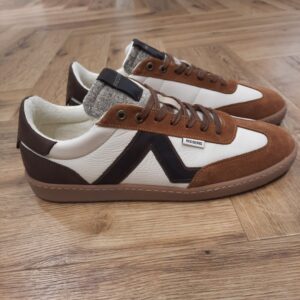 Redskins Eldorado Cognac La Redskins Eldorado Cognac décline le trainer rétro dans un daim beige lumineux, relevé de cognac sur le talon et la languette. Tout d'abord, la bande latérale blanche trace la ligne du modèle, que le col matelassé vient adoucir. Puis, la semelle gomme caramel, à débord dentelé, assoit la silhouette. Ces baskets se porte avec un jean clair, un chino écru ou un short en toile, du printemps à l'automne. L'histoire de la marque Lorsque l’on parle de la célèbre marque de cuir Redskins, on pense immédiatement au look américain, au style biker avec ce petit côté rock’n roll qui souligne la tenue masculine. Or c’est bel et bien en France qu’est née la marque, créée par Serge ABOUJEDID. C’est donc en 1984 que la marque Redskins voit le jour, inspirée de la culture américaine et de la tendance rock’n roll, empreint d’une touche contemporaine dans chaque création de la marque. Cette marque résolument française est née à Gennevilliers et oriente ses collections vers la fabrication de blousons et vestes en cuir pour homme. A partir des année 90, la marque a mis au gout du jour le modèle teddy Redskins, qui n’a de cesse d’être la pièce indémodable de votre garde-robe.