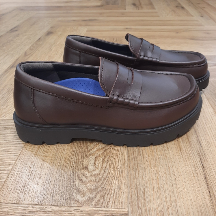 Highwood Loafer Chocolat Les Birkenstock Highwood Loafer Chocolat allient le style intemporel des mocassins et le confort emblématique des Birkenstock. En effet, le modèle réinterprète la forme Penny classique et offre la combinaison parfaite entre élégance et fonctionnalité, convenant parfaitement à un port quotidien. D'abord, le lit de pied Deep Blue, confortable et léger, rend ces chaussures agréables à porter en toutes circonstances, surtout durant de longues journées bien chargées. Puis, l’élément distinctif de cette variante est sa semelle en caoutchouc de grande qualité, dont le profil inspiré du monde professionnel offre une excellente adhérence. De plus, les éléments profilés, placés de manière à soutenir les propriétés biomécaniques du pied, favorisent son déroulement naturel et assurent un maximum de confort lors de la marche. Enfin, la tige se compose d’un cuir aniline haut de gamme et particulièrement brillant. L’histoire de Birkenstock Tout commence en 1774, lorsque Johann Adam Birkenstock, un cordonnier allemand passionné, fonde ce qui allait devenir l'une des marques de chaussures les plus emblématiques au monde. À l'époque, Johann menait une petite entreprise modeste qui lui permettait de vivre confortablement. Mais comment cette production familiale a-t-elle pu se transformer en un empire mondial de la chaussure ? Le tournant se produit en 1896 avec Konrad Birkenstock, un descendant de la famille. Konrad, visionnaire, décide de donner un coup de jeune à l'entreprise familiale. C'est lui qui a développé la première semelle intérieure orthopédique, une innovation qui a littéralement mis le sabot Birkenstock sur la carte mondiale. Cependant, il aura fallu plusieurs générations et une évolution constante pour que Birkenstock devienne la marque internationale que l'on connaît aujourd'hui. Le grand bond en avant s’est produit au XXe siècle, notamment aux États-Unis dans les années 1960, où les sandales Birkenstock sont devenues un symbole de la contre-culture et du confort.
